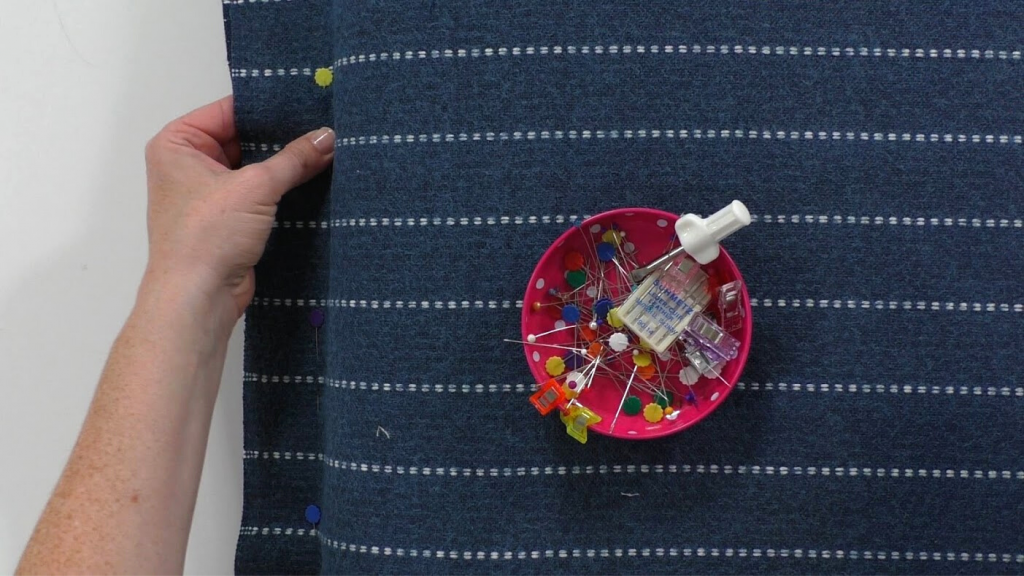 woman adding sewing pins to fabric for cushion