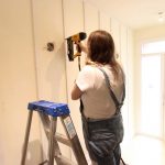 woman nailing vertical boards on wall
