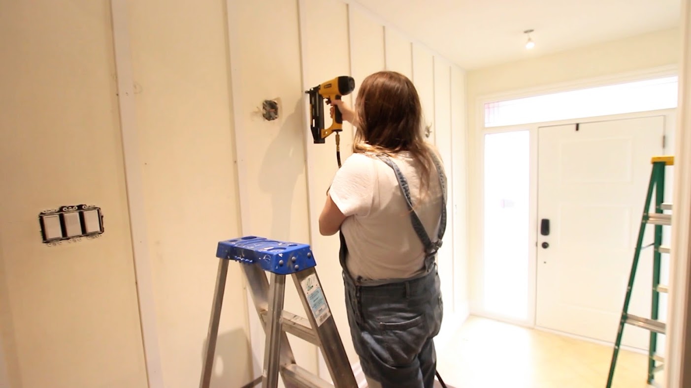 woman nailing vertical boards on wall